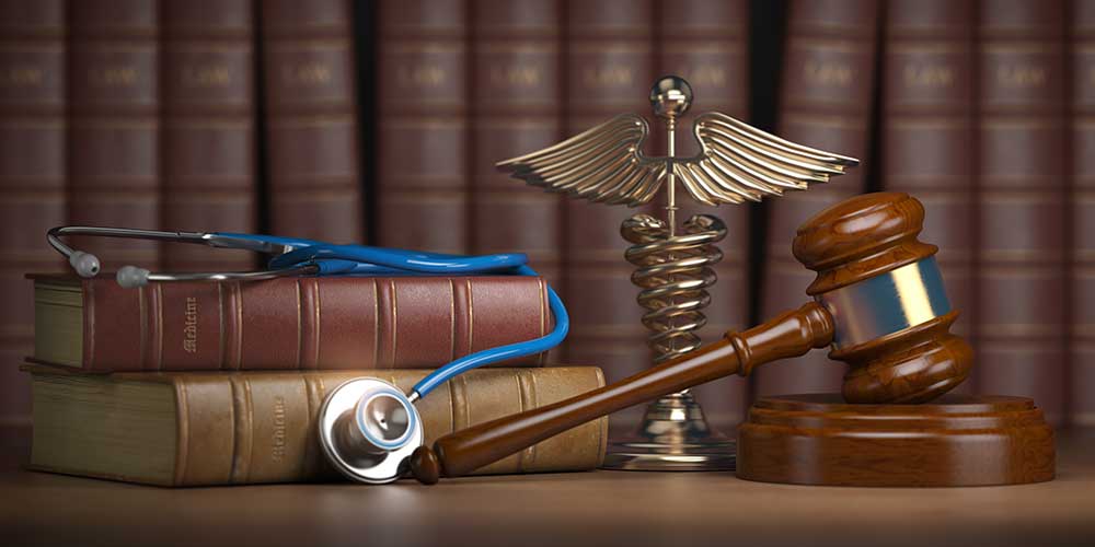 Gavel and caduceus with a stethoscope lying on textbooks