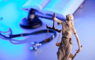 Figure of justice with scales and gavel and personal injury book in background