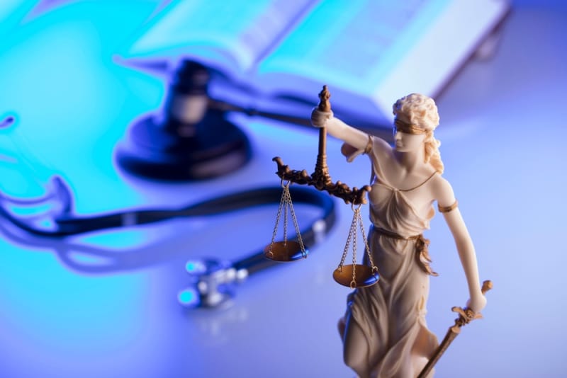 Figure of justice with scales and gavel and personal injury book in background
